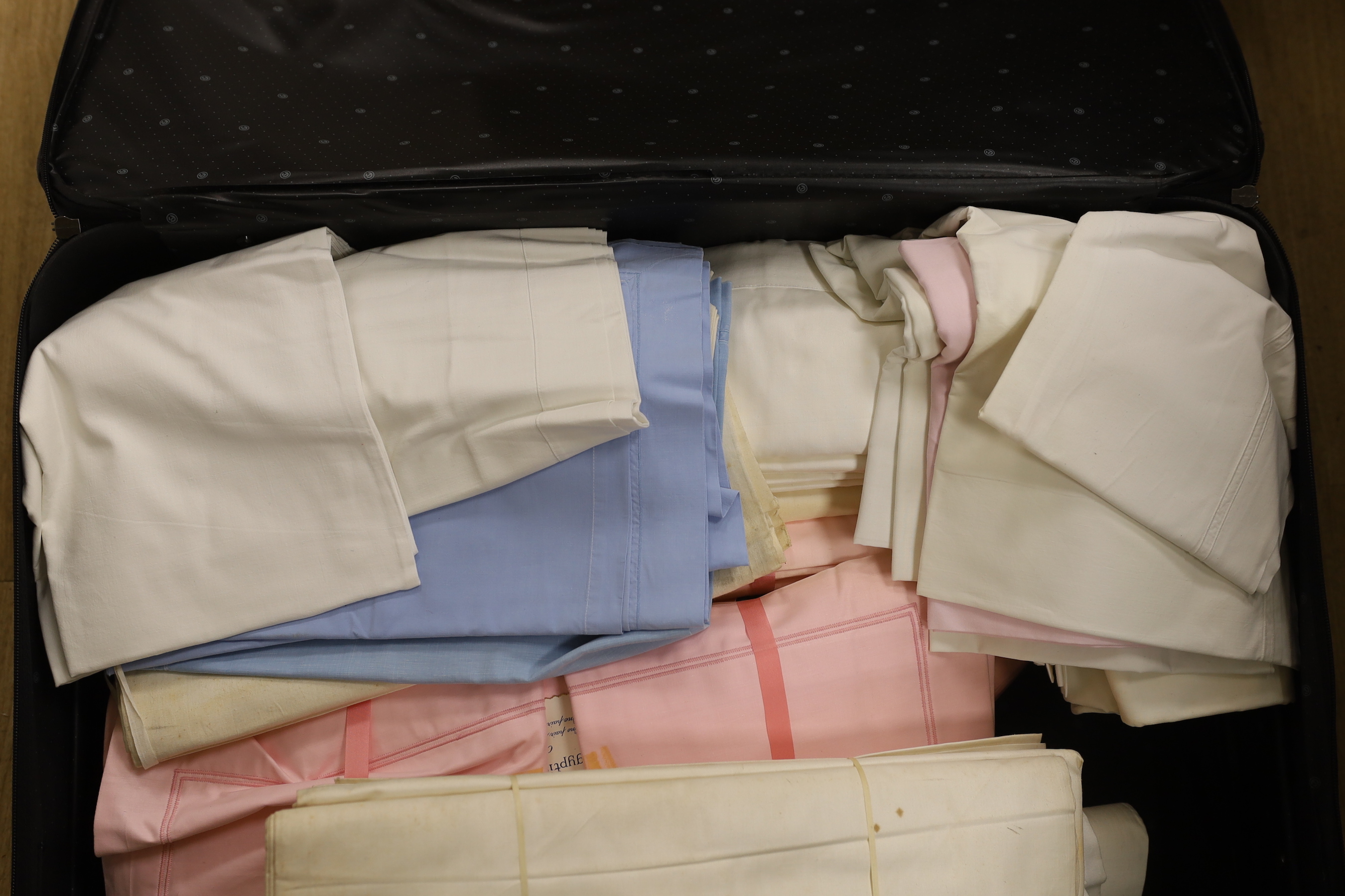 A suitcase of various coloured, unused cotton sheets